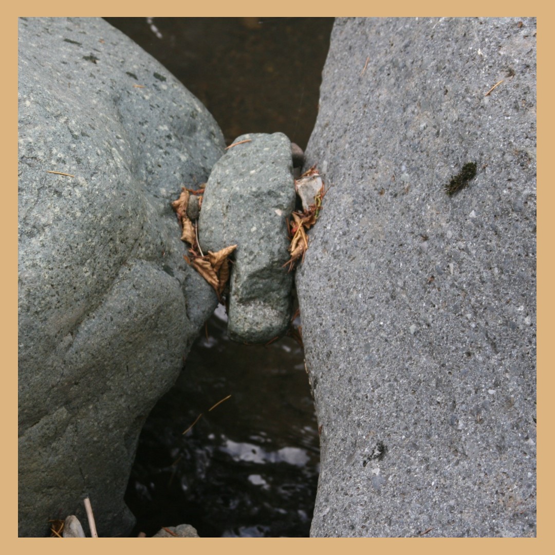 Photo of a small rock suspended between two rocks